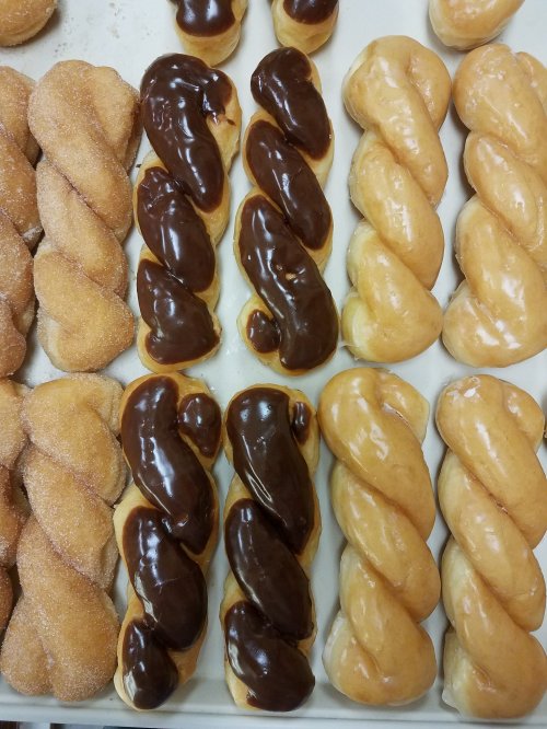 A tray of assorted donuts: twisted glazed, chocolate-covered, and sugared varieties arranged neatly.