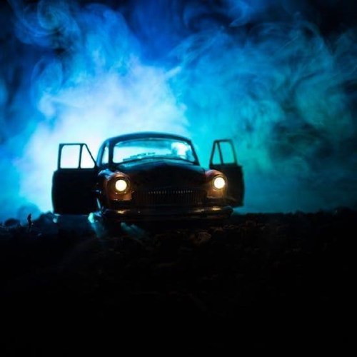 A vintage car with open doors sits in a misty, blue-lit environment, creating a mysterious atmosphere.