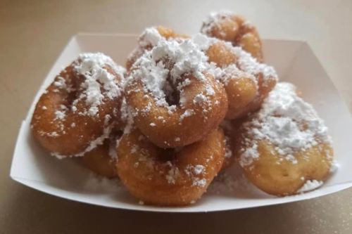 A plate of small, round donuts dusted with powdered sugar.