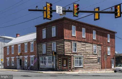 Historic building at a traffic intersection, featuring a mix of brick and log construction, with traffic lights above.