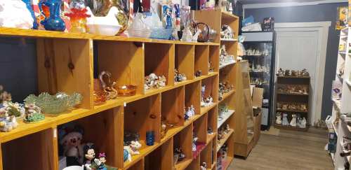 A cozy shop interior featuring wooden shelves filled with various collectibles and decorative items.