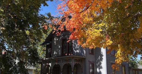 A charming gray house surrounded by vibrant autumn leaves in shades of orange and yellow.