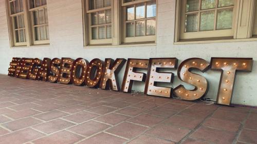 Illuminated marquee letters spelling "BOOK FEST" arranged on a tiled floor, with warm lights glowing.