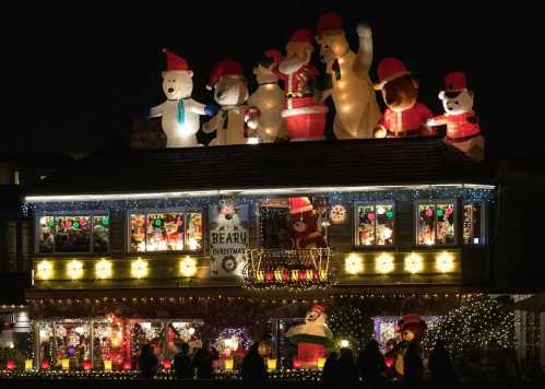 A festive house adorned with colorful Christmas lights and large inflatable decorations on the roof.