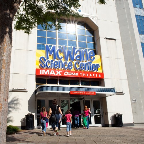 A group of children approaches the entrance of the McWane Science Center, featuring an IMAX Dome Theater sign.