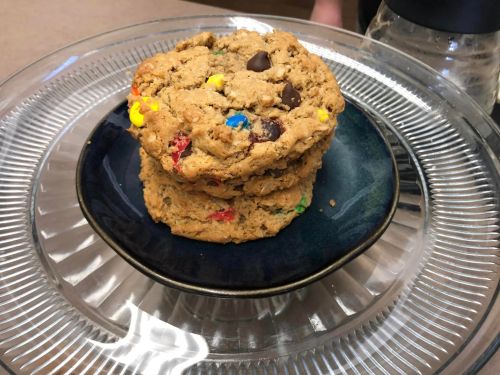 A stack of large, colorful cookies on a blue plate, displayed on a glass platter.