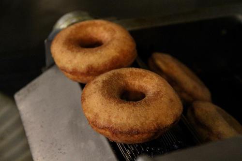 Freshly fried donuts cooling on a rack, golden brown with a fluffy texture.