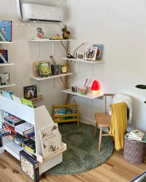 Cozy reading nook with shelves of books, a chair, a soft rug, and a warm lamp in a bright, inviting space.