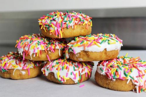A stack of colorful donuts topped with white icing and vibrant sprinkles.