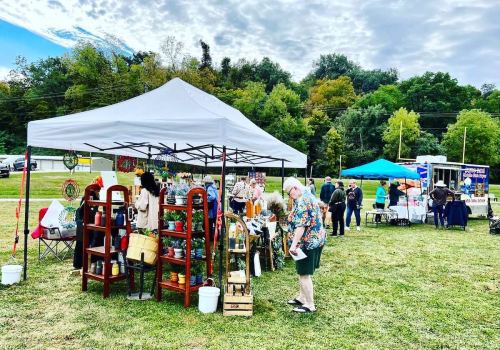 A vibrant outdoor market scene with tents, vendors, and shoppers browsing various handmade goods and crafts.