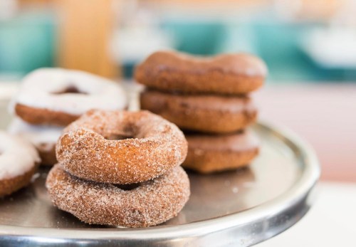 A tray of assorted donuts, including cinnamon sugar and chocolate, stacked and ready to be served.