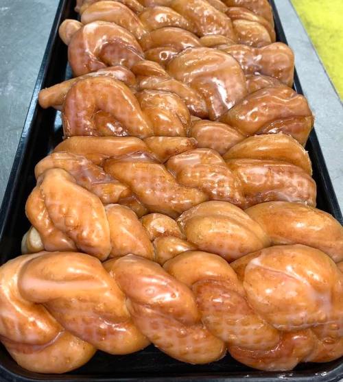 A tray of glazed, braided pastries with a shiny, golden-brown finish.