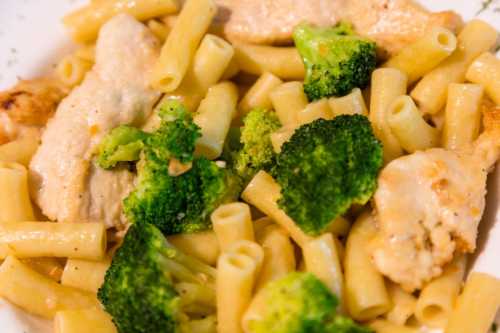 A plate of pasta with broccoli and pieces of chicken in a creamy sauce.