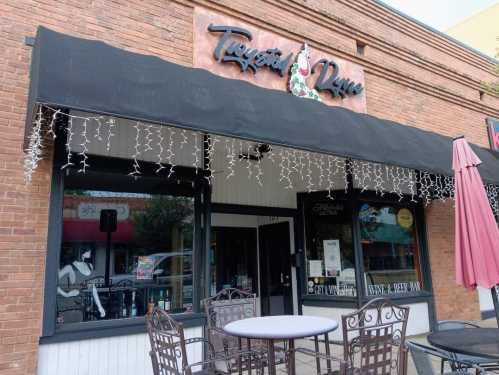 Exterior of a restaurant with a sign reading "Pizzazz Dine," featuring outdoor seating and festive lights.