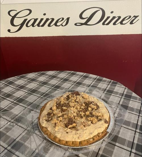 A delicious pie topped with crumbled cookies sits on a table in front of a "Gaines Diner" sign.