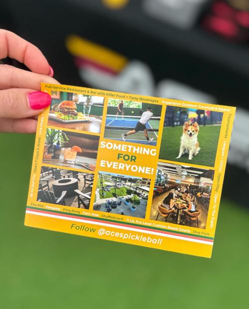 A hand holding a colorful flyer promoting a pickleball venue with food, drinks, and outdoor space.