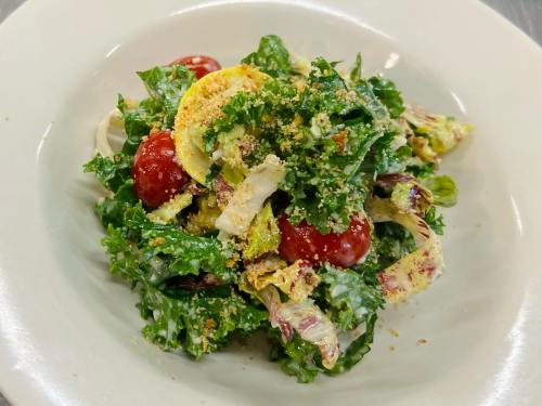 A fresh salad with mixed greens, cherry tomatoes, and a sprinkle of grated cheese on a white plate.