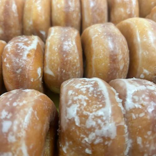 A close-up of glazed donuts arranged in a row, showcasing their shiny, sugary surface.