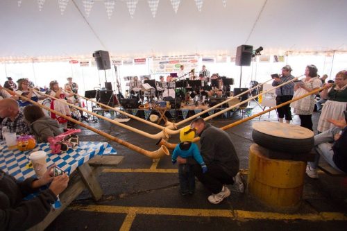 A lively festival scene with a band playing, people enjoying the event, and a child interacting with an adult.
