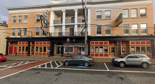 Historic building with a theater entrance, red and yellow facade, and parked cars on a street.