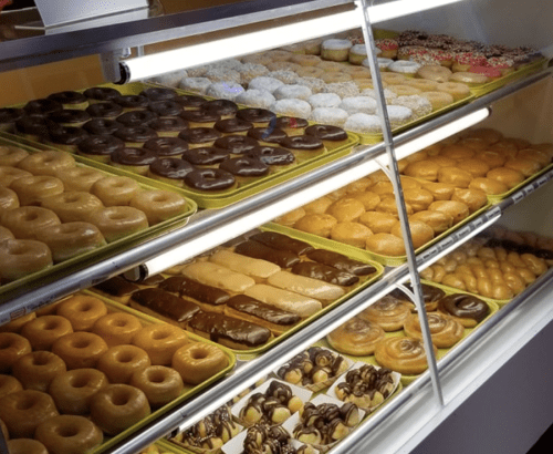 A display case filled with various donuts, including glazed, chocolate-covered, and sprinkled varieties.