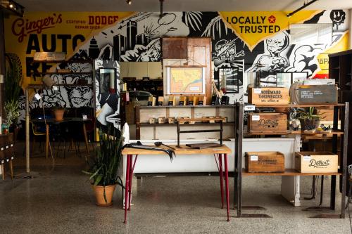 A vibrant auto repair shop interior with a mural, wooden furniture, and plants, showcasing a mix of vintage and modern decor.