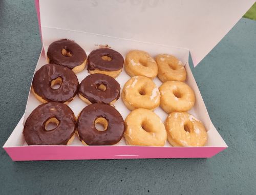 A box of assorted donuts, featuring chocolate-covered and glazed varieties, arranged neatly in two rows.