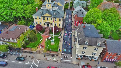 Aerial view of a vibrant street with people walking, surrounded by historic buildings and lush green trees.