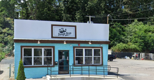 A light blue building with a sign reading "Dough Bros," featuring large windows and a ramp in front.