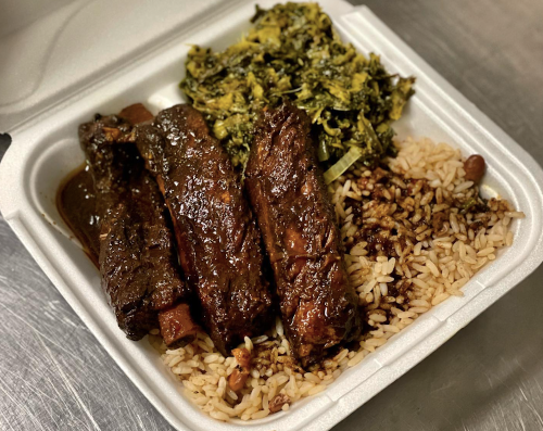 A takeout container with rice, beans, braised greens, and four pieces of glazed beef ribs.