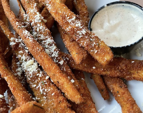 Crispy golden-brown fries sprinkled with cheese, served with a small bowl of dipping sauce.