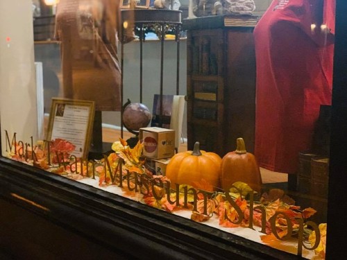 Window display of the Mark Twain Museum Shop featuring pumpkins and autumn leaves.