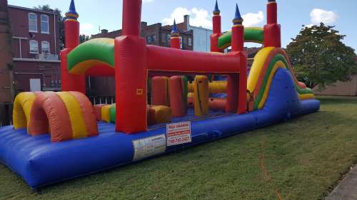 A colorful inflatable bounce house with slides and arches set up on a grassy area.