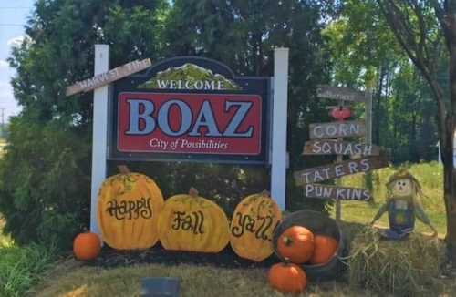 Welcome sign for Boaz, featuring pumpkins, hay, and fall decorations with the text "Happy Fall Y'all."