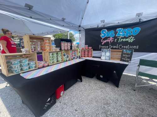 A market stall displaying colorful freeze-dried treats in containers, with a banner reading "Sub Zero Sweets & Treats."