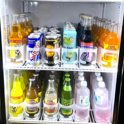 A refrigerator filled with various colorful soft drinks and juices in bottles and cans on multiple shelves.