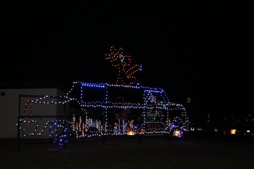 A festive display of colorful lights featuring a figure on top of a truck, set against a dark night sky.
