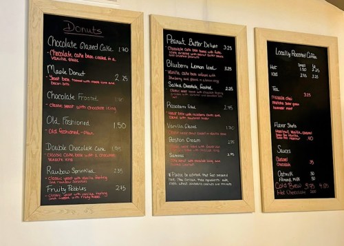 Menu boards displaying various donut options and prices, including flavors like chocolate, maple, and blueberry.