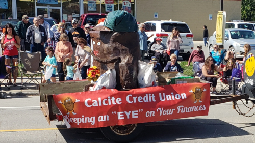 A parade float featuring a large, cartoonish eye with a sign for Calcite Credit Union promoting financial awareness.