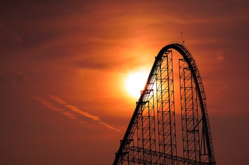 Silhouette of a roller coaster against a vibrant sunset sky.