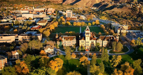 Aerial view of a university campus with historic buildings, green lawns, and autumn foliage.