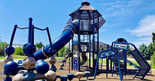 A blue playground featuring a tall tower, slides, and climbing structures under a clear blue sky.