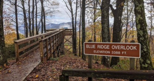 A wooden overlook platform in the Blue Ridge Mountains, surrounded by trees and autumn foliage, with a sign indicating elevation.