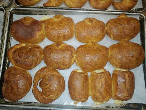 A tray of freshly baked golden-brown pastries arranged in rows on parchment paper.