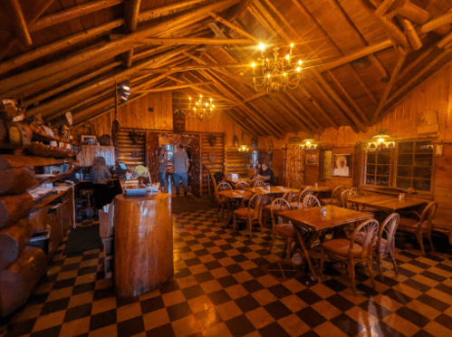 Cozy wooden interior of a rustic restaurant with checkered floor, tables, and warm lighting.