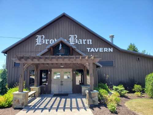 Exterior of a rustic tavern named "Brook Barn," featuring a wooden entrance and landscaped surroundings.