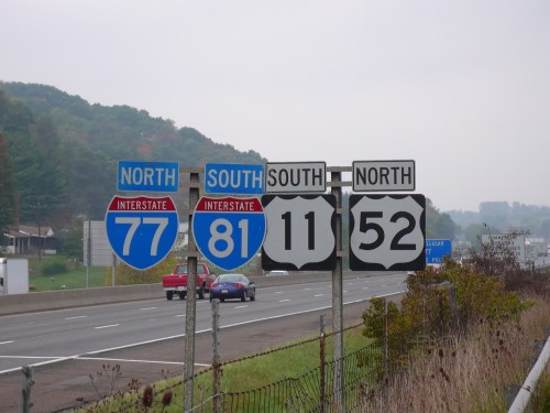 Interstate highway signs for I-77 North, I-81 South, and routes 11 and 52, with a foggy landscape in the background.
