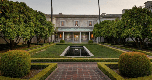 A grand mansion surrounded by lush greenery and neatly trimmed hedges, featuring a central reflecting pool.