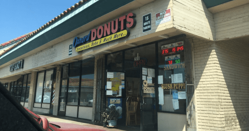 A storefront for "Daniel's Donuts" featuring a menu sign and a digital display of prices.