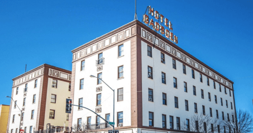 Historic hotel building with a prominent sign against a clear blue sky.